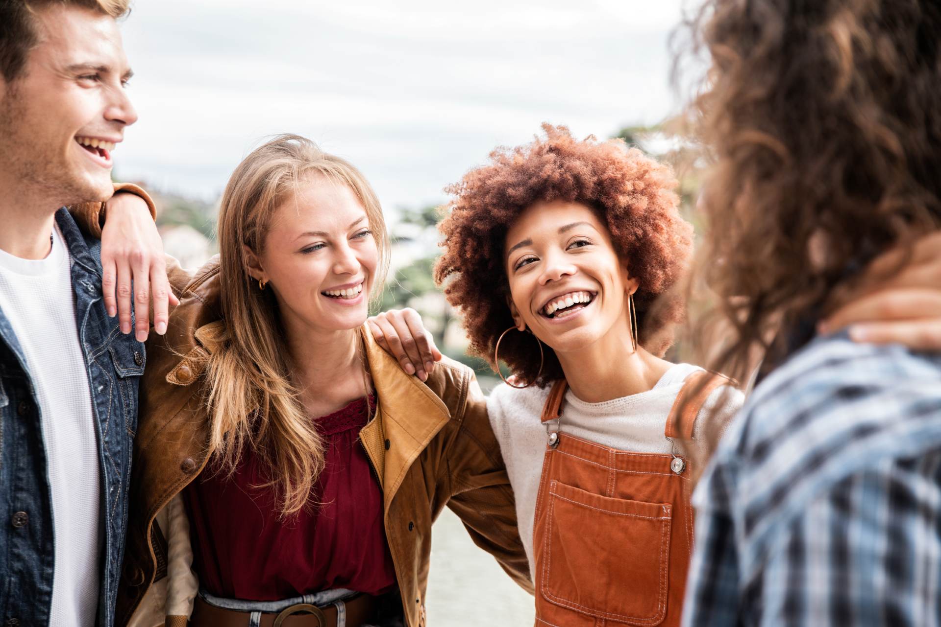 Group of multiracial best friends laughing together outdoor